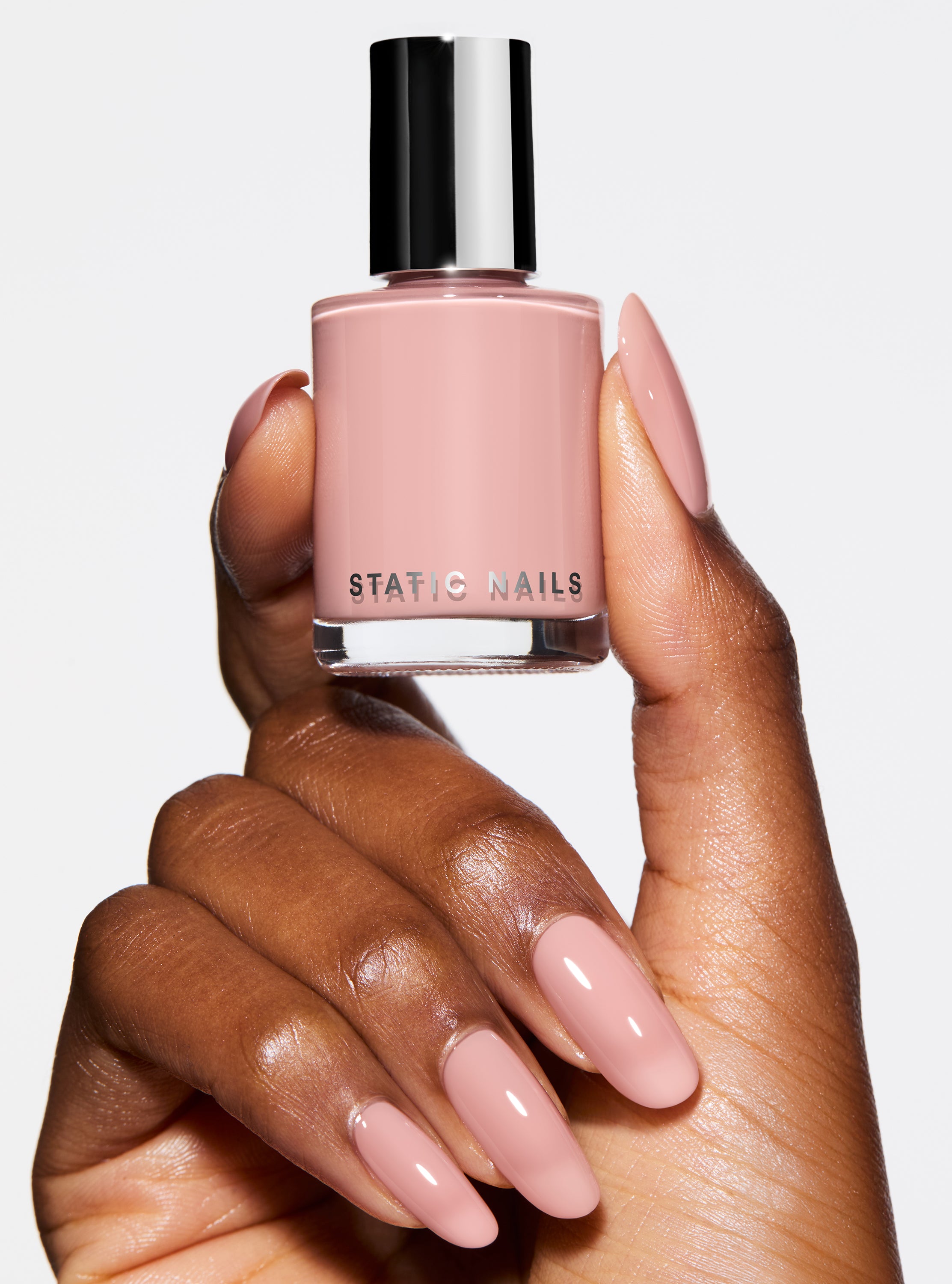 Hand holding a bottle of pink nail polish with &