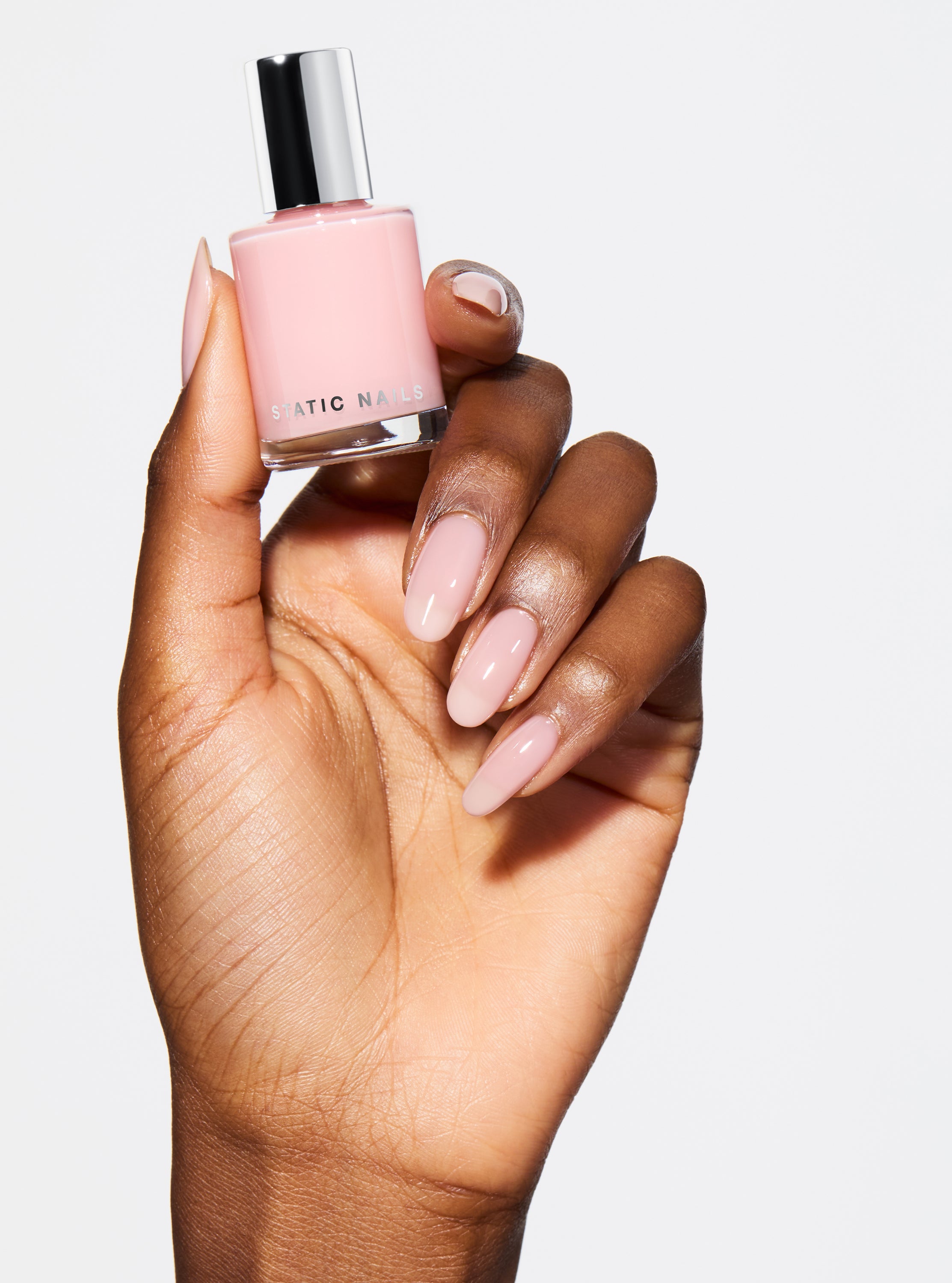 Hand with pink nail polish on a pink background