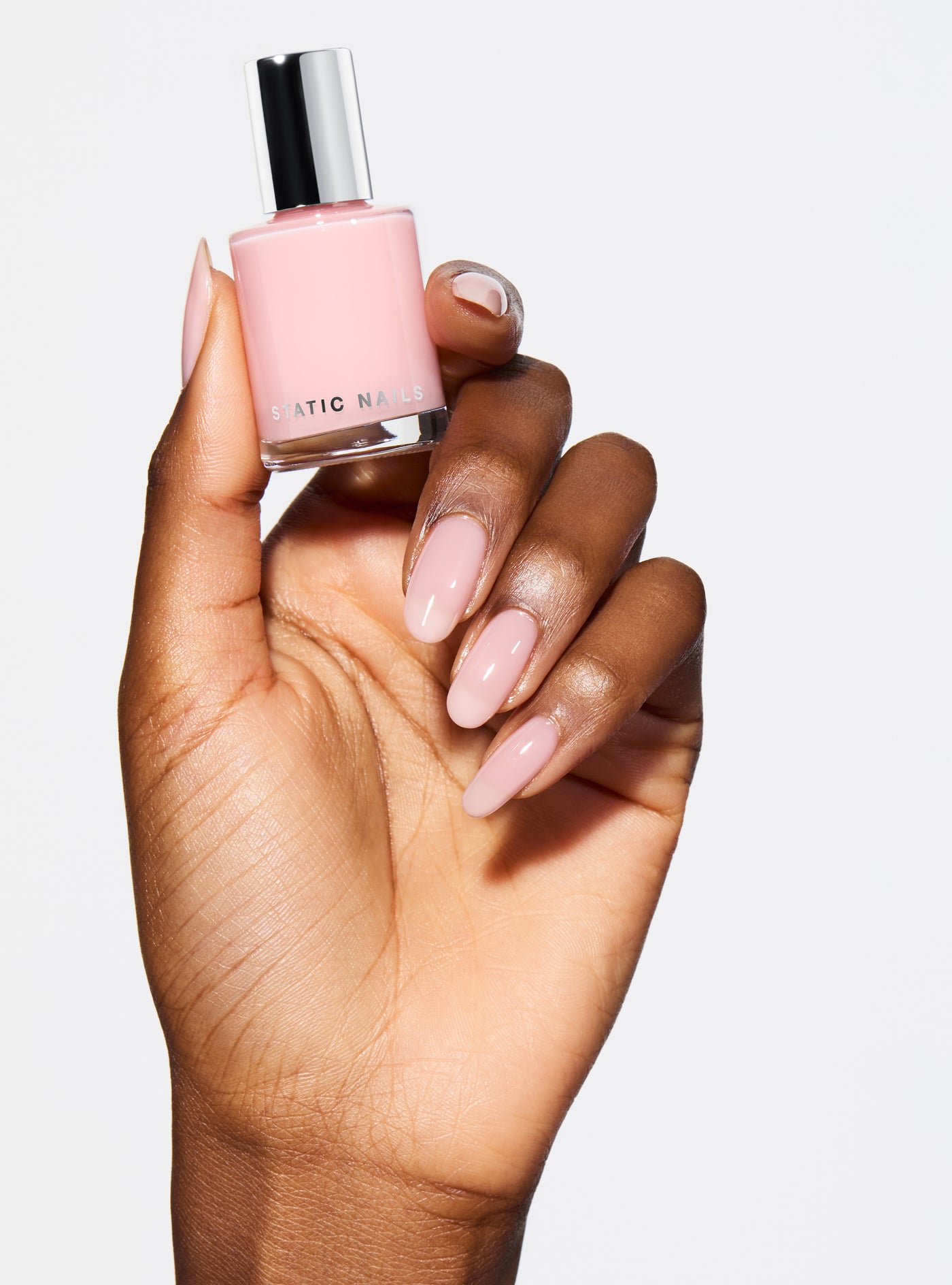 Hand with pink nail polish on a pink background