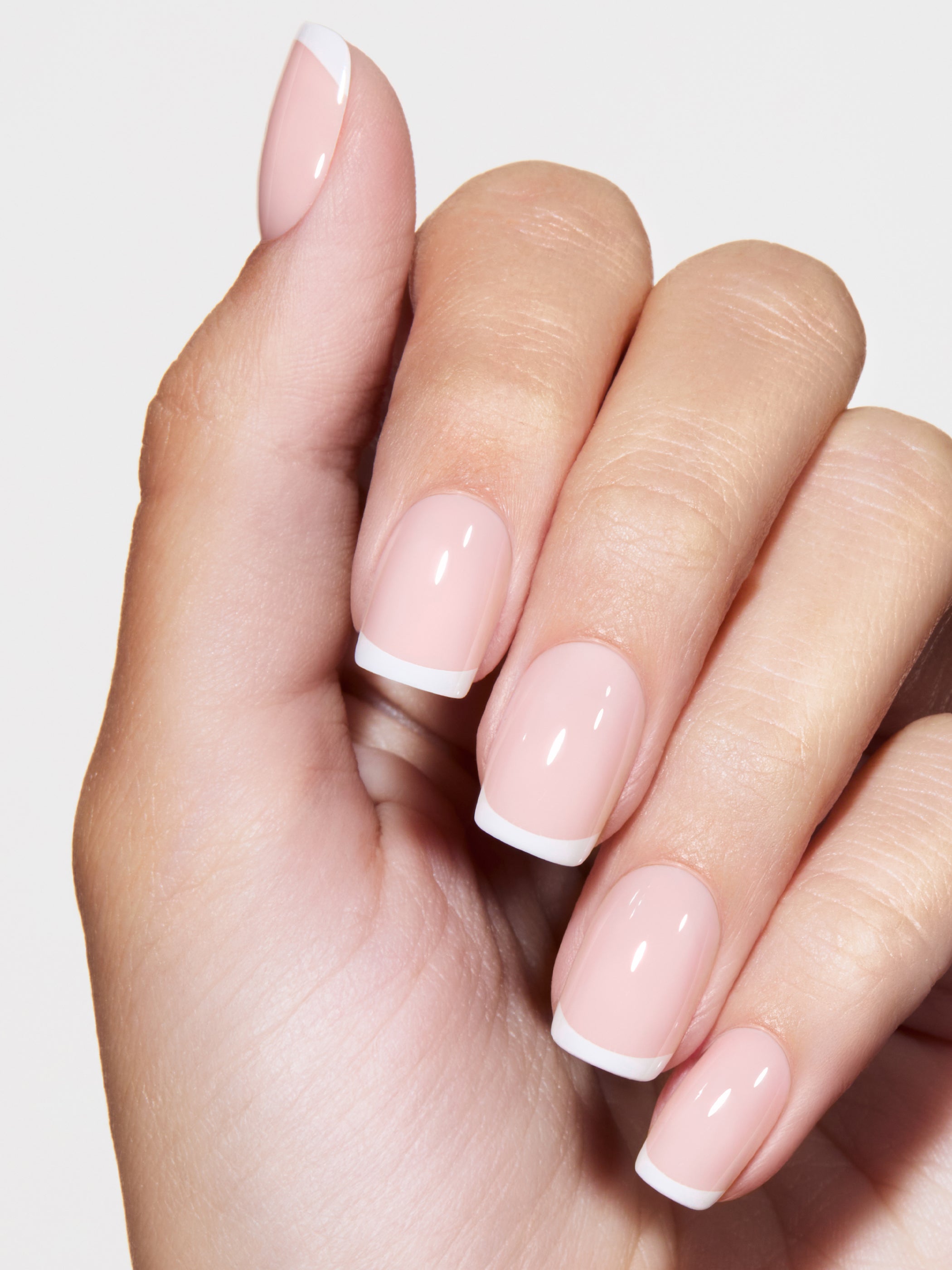 Close-up of a hand with pink nail polish on a light background