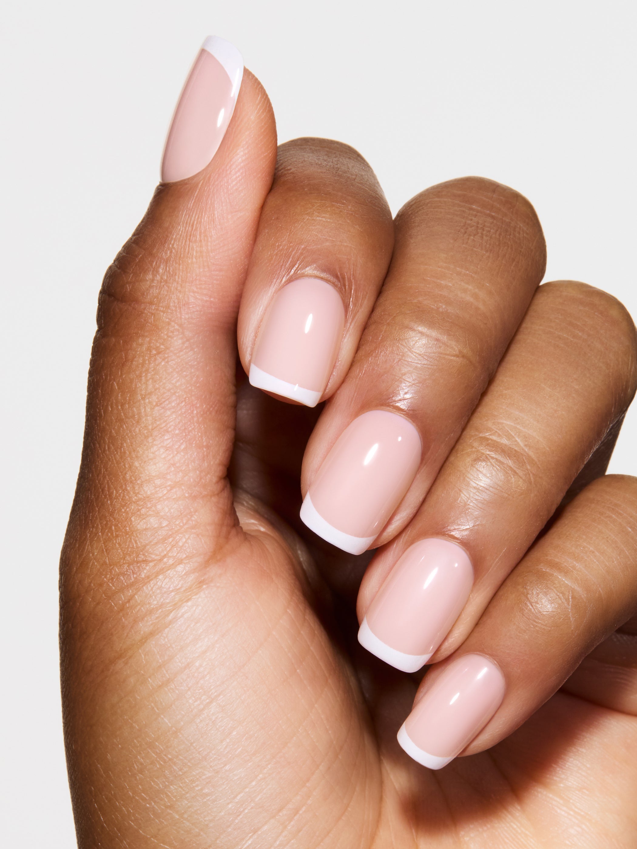 Hand with pink nail polish on a light background