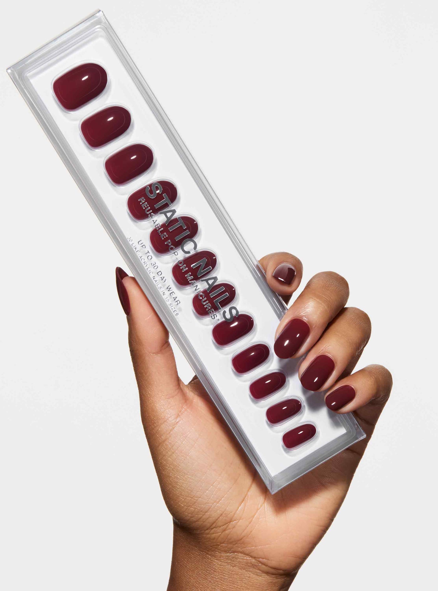 Set of red nail pads in a clear plastic case held by a hand with matching nails.