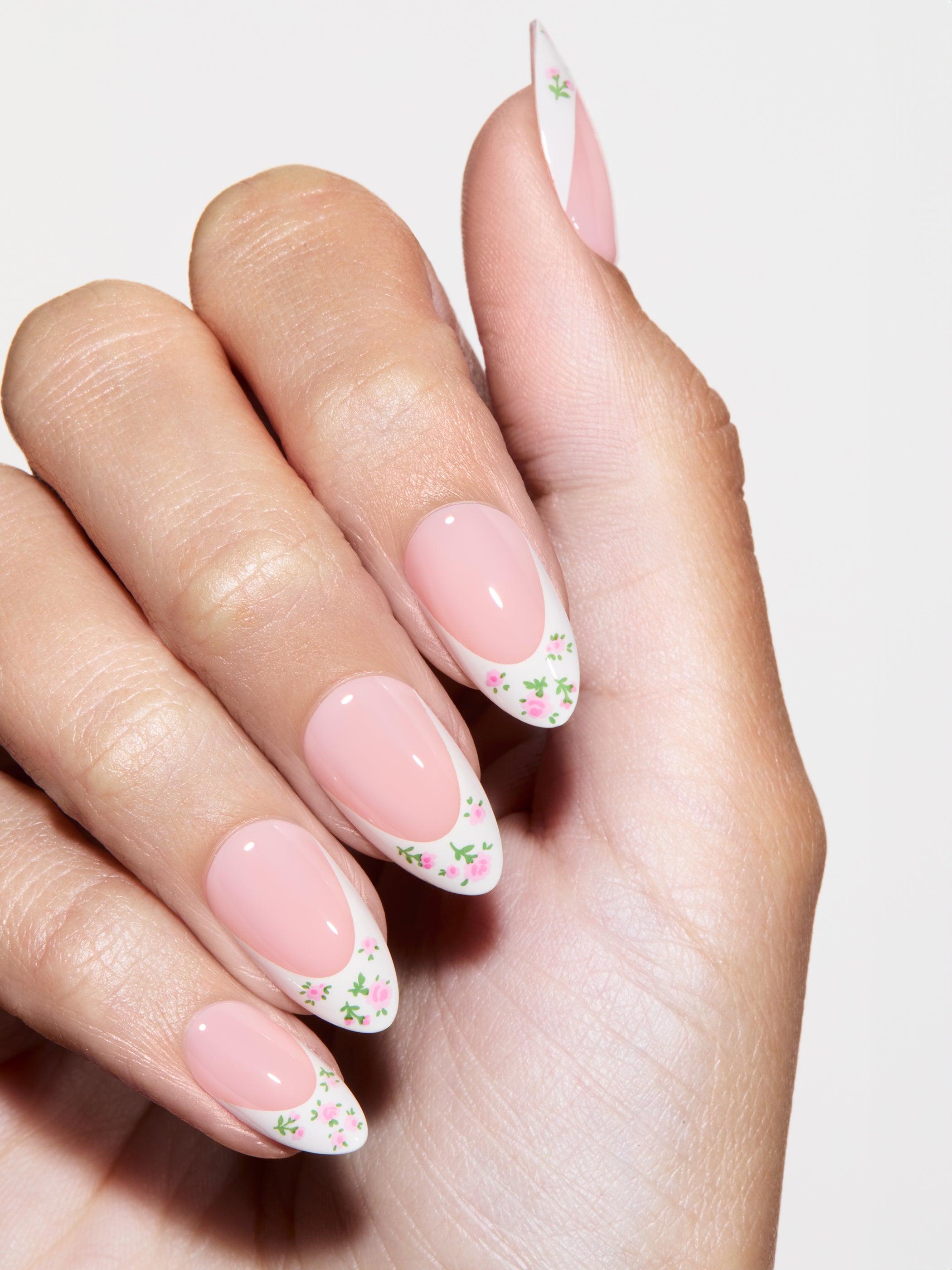 Hand with pink nails and floral design on a light background
