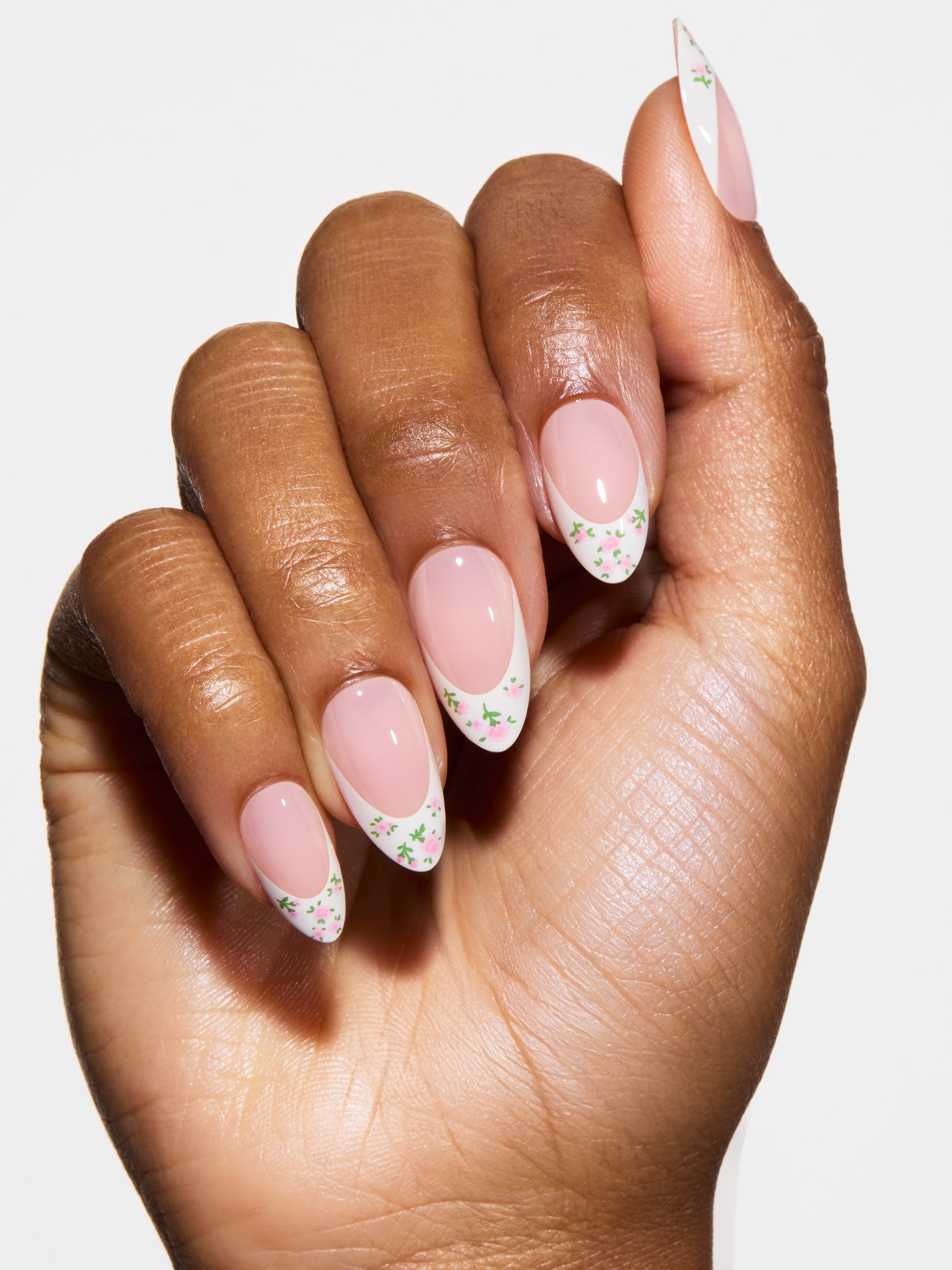 Hand with pink nails and floral designs on a white background