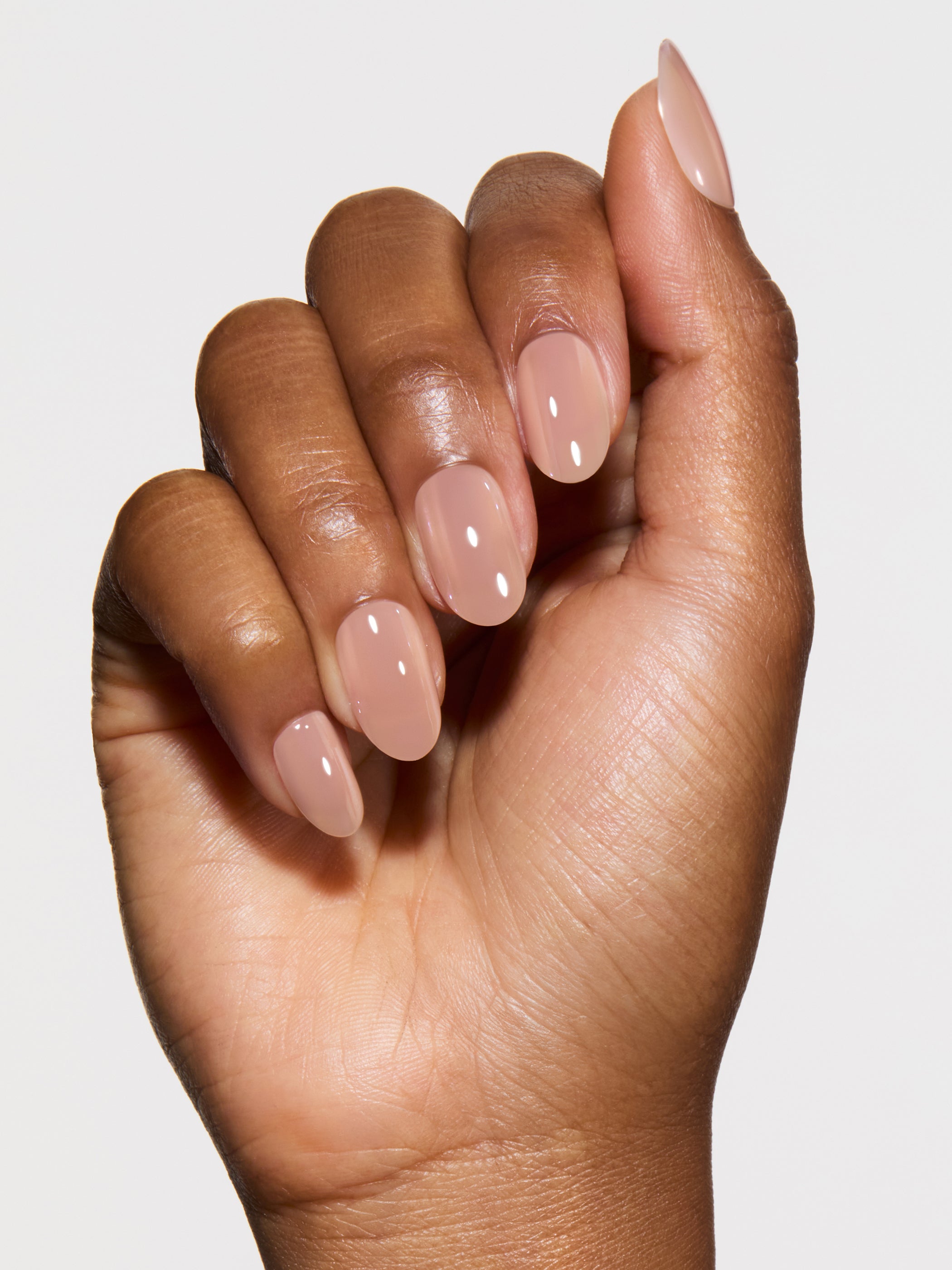 Hand with nude-colored nail polish on a plain background