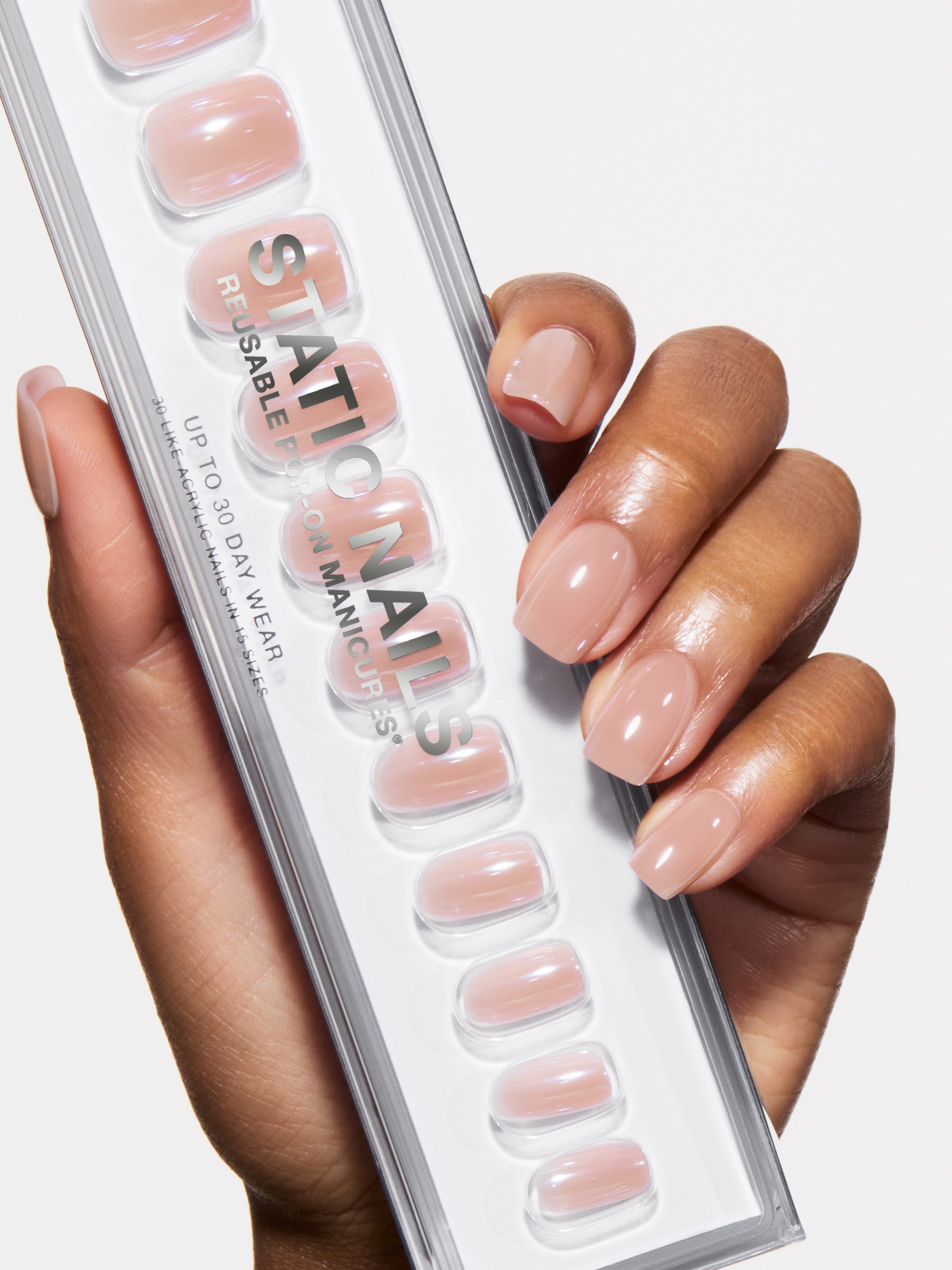Hand holding a set of press-on nails with a neutral color palette.