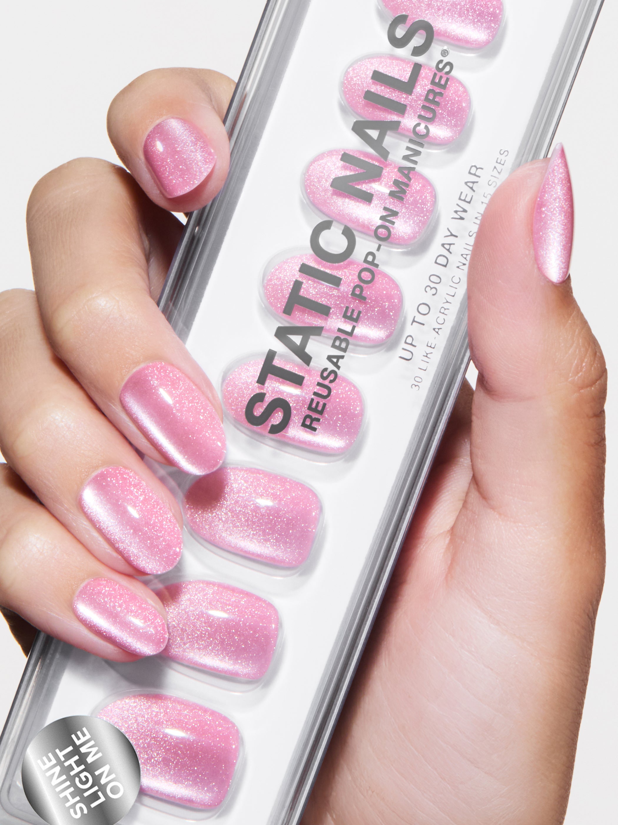 Hand holding a pack of pink Static Nails with matching nails.