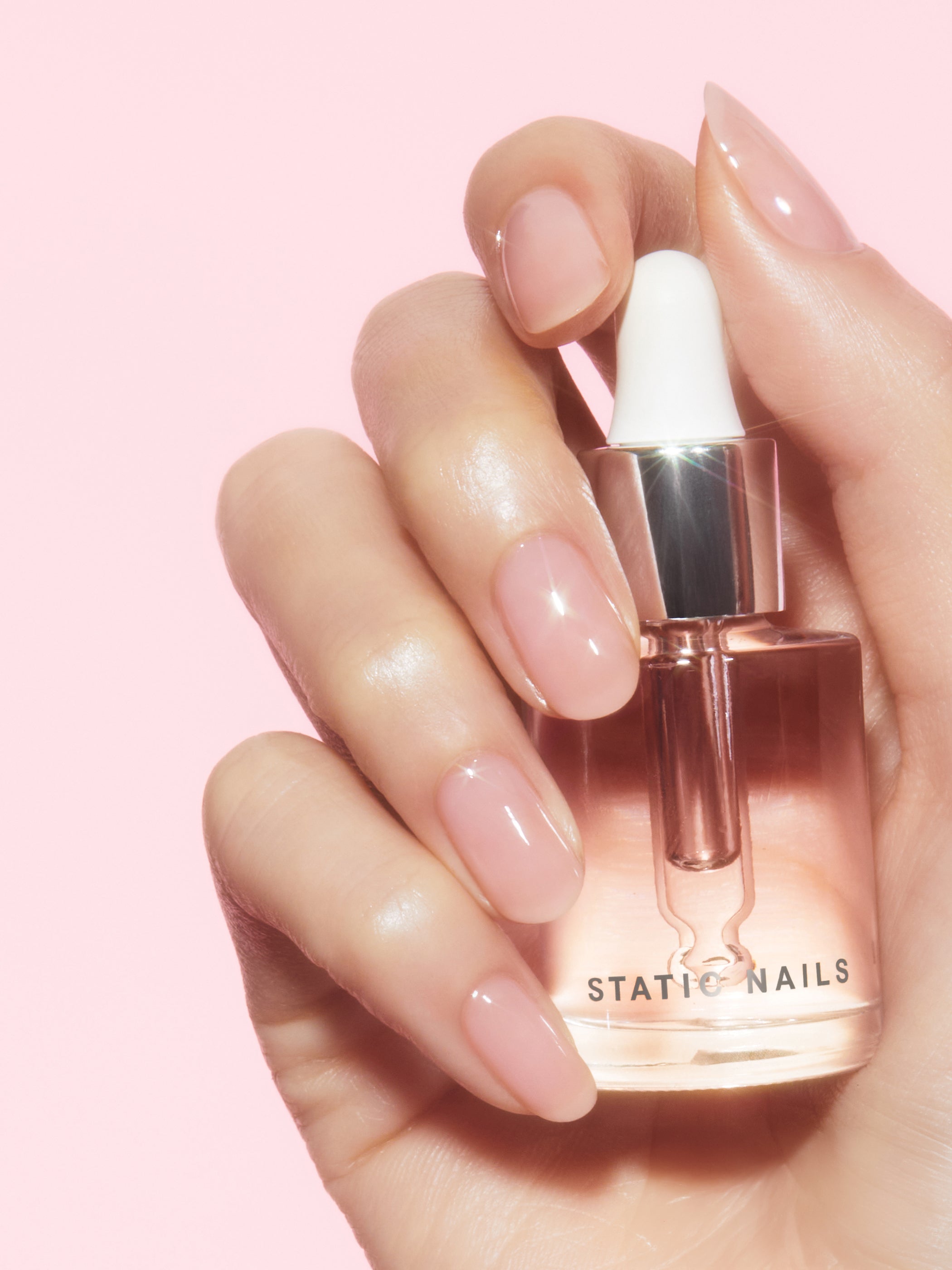 Hand with pink nail polish on a pink background
