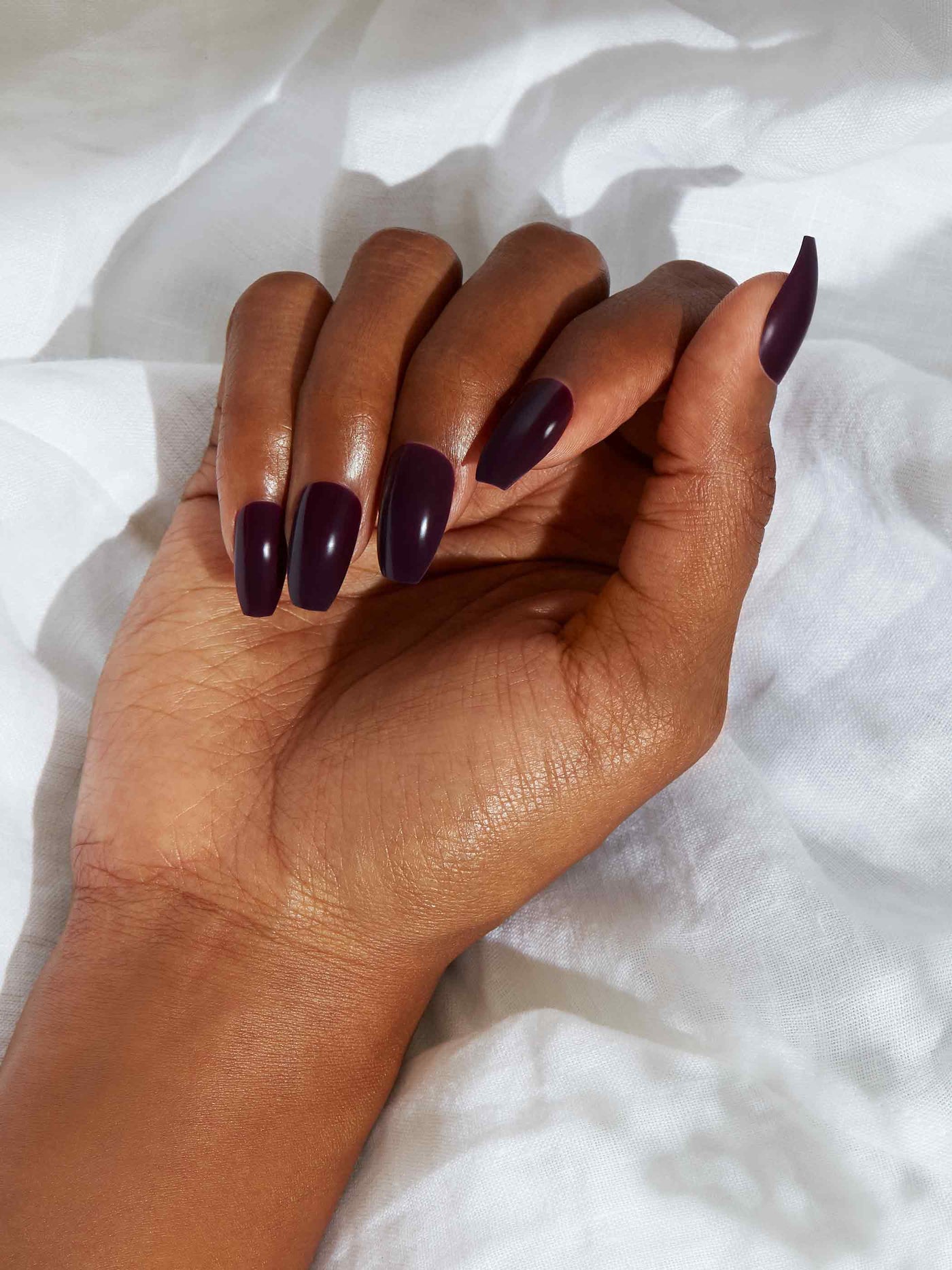 Blackened plum manicure in coffin shape,